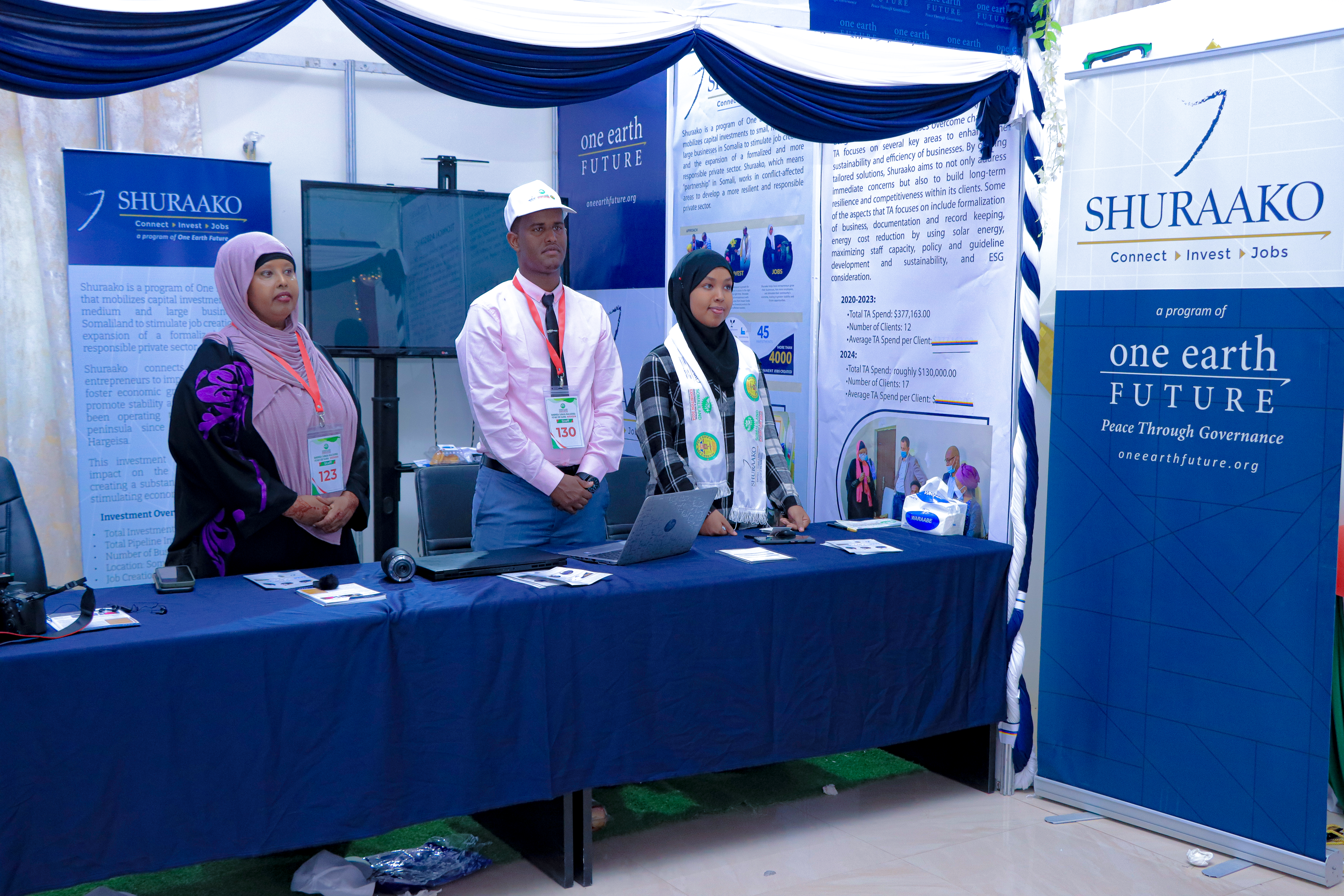 3 Shuraako employees standing at a booth waiting for the Somaliland Investment Expo to begin!