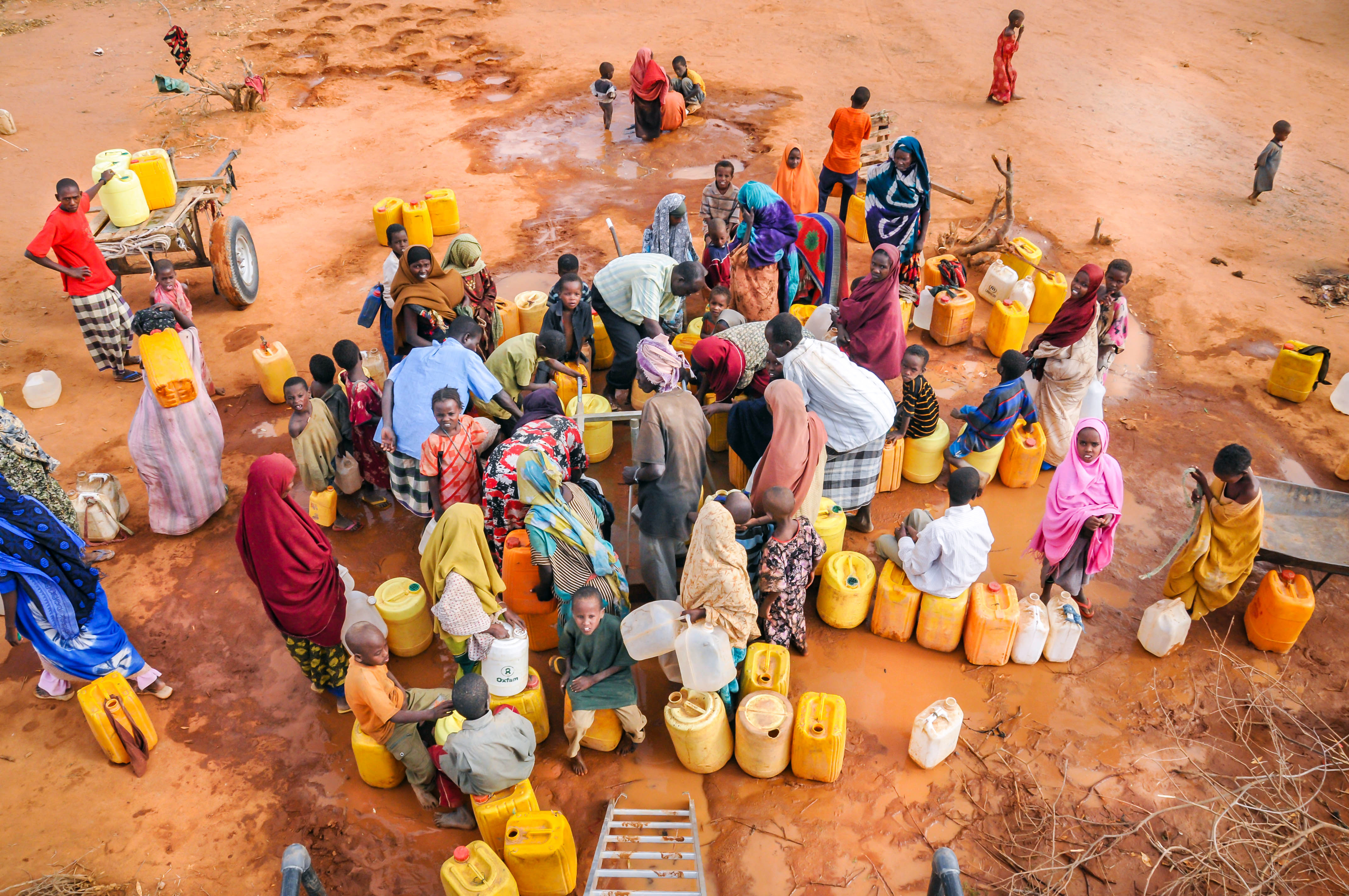 People gathering with water containers in a community