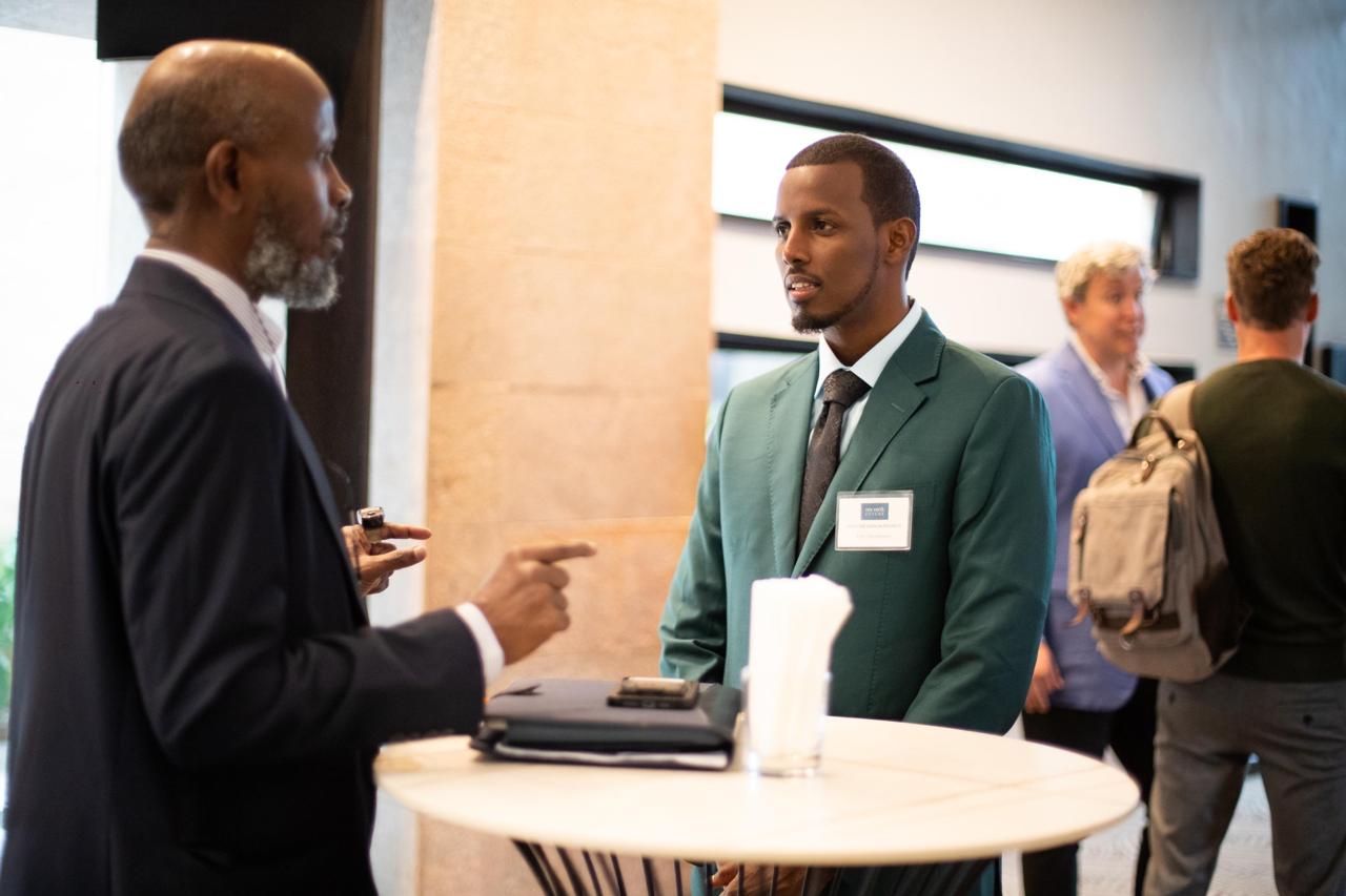 2 event guests having a discussion standing at a small round table.