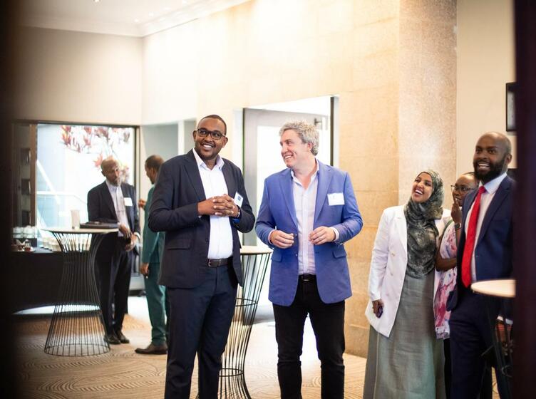 Event photo of OEF Executive Director and Shuraako Director standing and smiling with a few other event guests before event begins