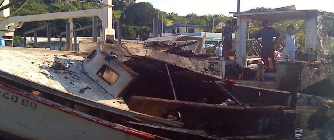 Puerto rican fishing family observers the burned ruins of their boat 