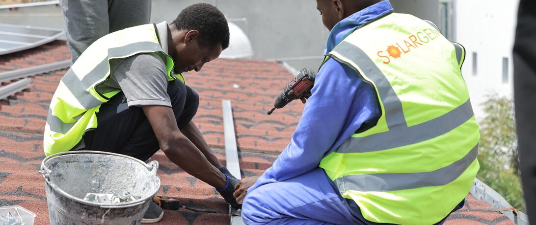 SolarGen construction workers and project managers attaching solar panels to the top of a roof