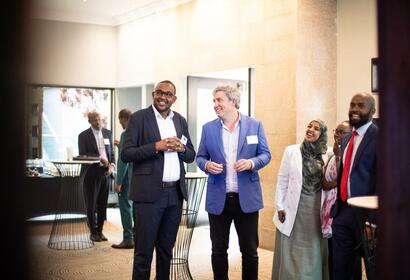 Event photo of OEF Executive Director and Shuraako Director standing and smiling with a few other event guests before event begins